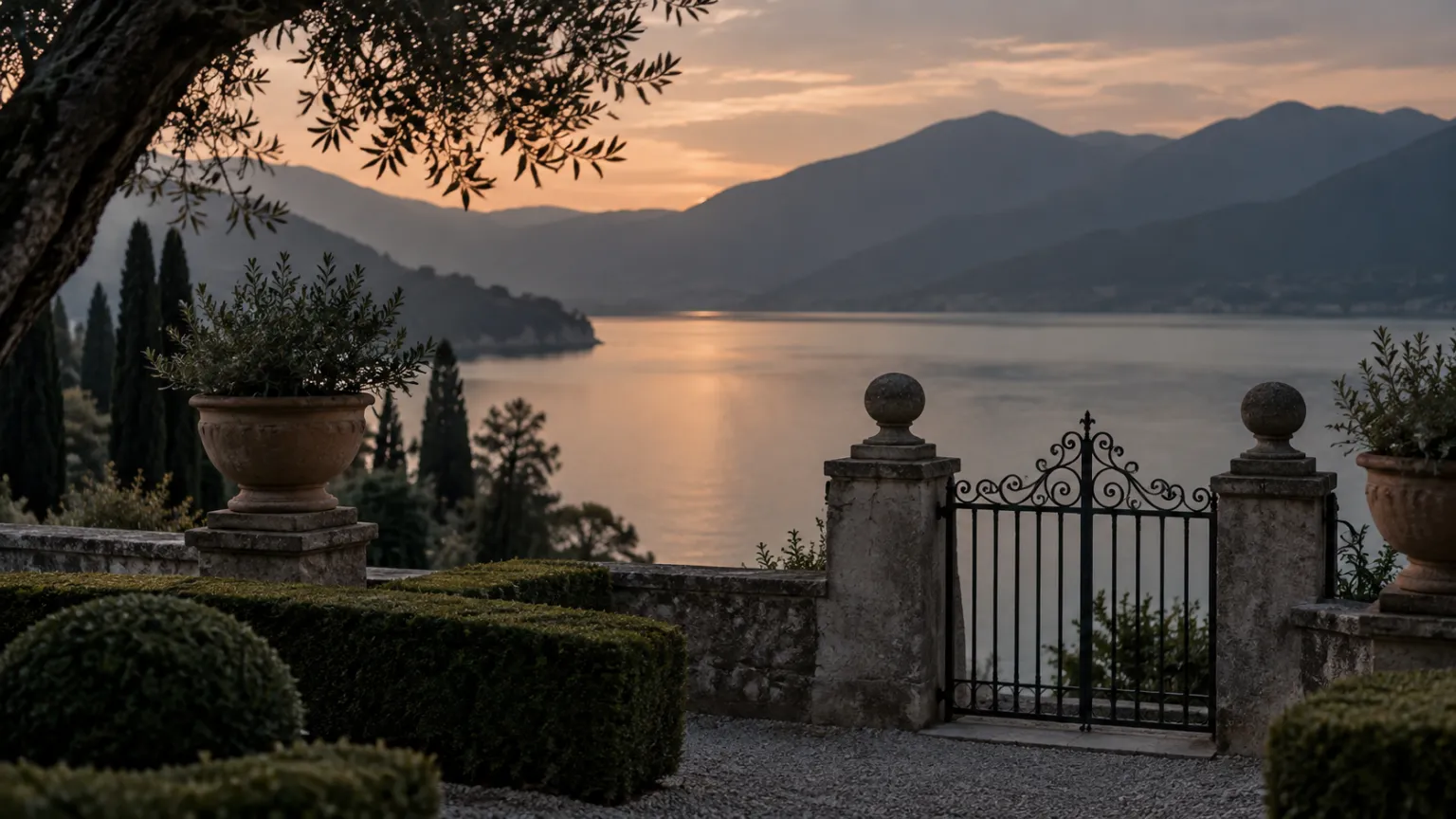 Illustration of a stone-walled lakeside garden terrace with clipped hedges and an iron gate at dusk, still water and hazy mountains beyond