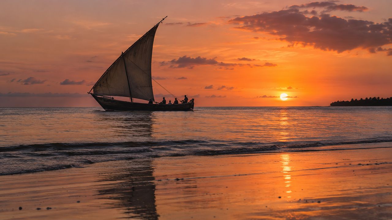 Illustration of a traditional dhow under sail at sunset off Zanzibar